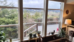 Ein Zimmer mit großen Fenstern und Blick auf eine Terrasse mit Ausblick auf eine hügelige Landschaft.