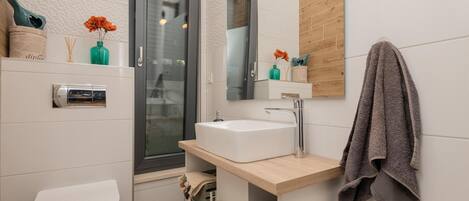 A modern bathroom with a toilet, sink, and shower.