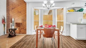 A dining area with a wooden floor, a chandelier, and a white kitchen in the background. - Luxury Loft Retreat: with Pool and Game room! (Houston)