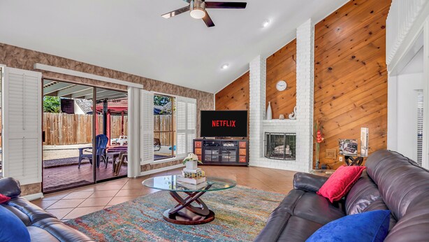 A spacious living room with a leather sofa, a glass coffee table, and a fireplace. - Luxury Loft Retreat: with Pool and Game room! (Houston)