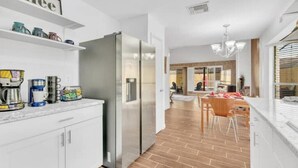 A modern kitchen with white cabinets, a stainless steel refrigerator, and a coffee station. - Luxury Loft Retreat: with Pool and Game room! (Houston)