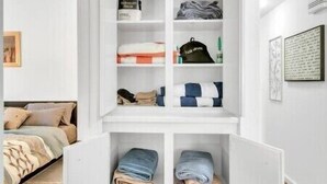 A white closet with shelves and drawers, containing folded clothes and storage boxes. - Luxury Loft Retreat: with Pool and Game room! (Houston)