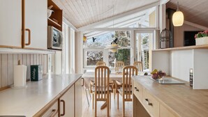 A modern kitchen with wooden cabinets, a central island, and a view of the outdoors through large windows. - 3 bedroom gorgeous home in Gilleleje (Gilleleje)