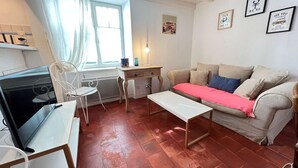 A compact living space with a sofa, a small table, a chair, and a TV.