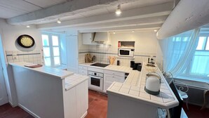 A kitchen with white cabinets, a microwave, a stove, and a clock on the wall.