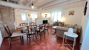 A spacious living area with a dining table, chairs, a sofa, and a small side table.