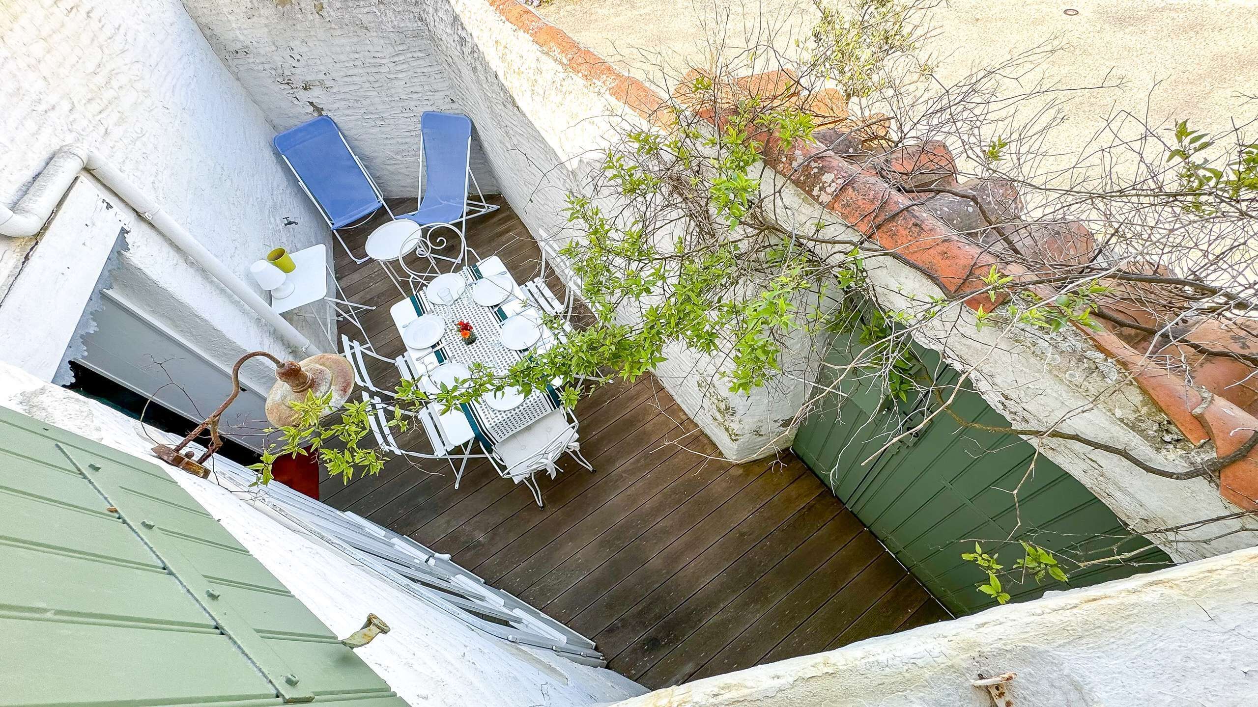 A small outdoor patio with a table and chairs, surrounded by a brick wall and a green gate.