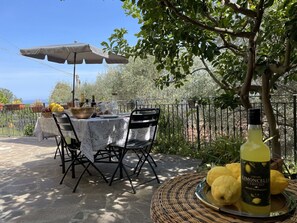 An outdoor dining area with a table set for two, surrounded by a metal fence and trees. - Nice apartment for 5 guests with WIFI and patio (Cipressa)