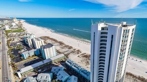 Un hotel frente al mar con varias construcciones, una playa y una vista despejada del océano.