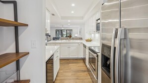 A modern kitchen with white cabinets, a stainless steel refrigerator, and a wooden floor. - 112 The Greens @ Shipyard | Golf, Tennis &  Pool | Walk to Beach (Hilton Head Island)