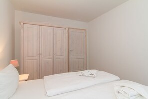 A bedroom with a bed, a nightstand, and a wardrobe.