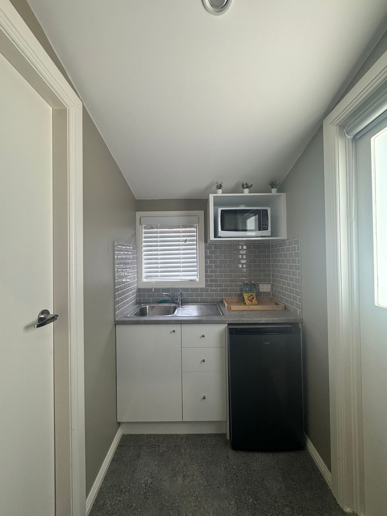 A compact kitchen with a built-in microwave, a sink, and a dishwasher.
