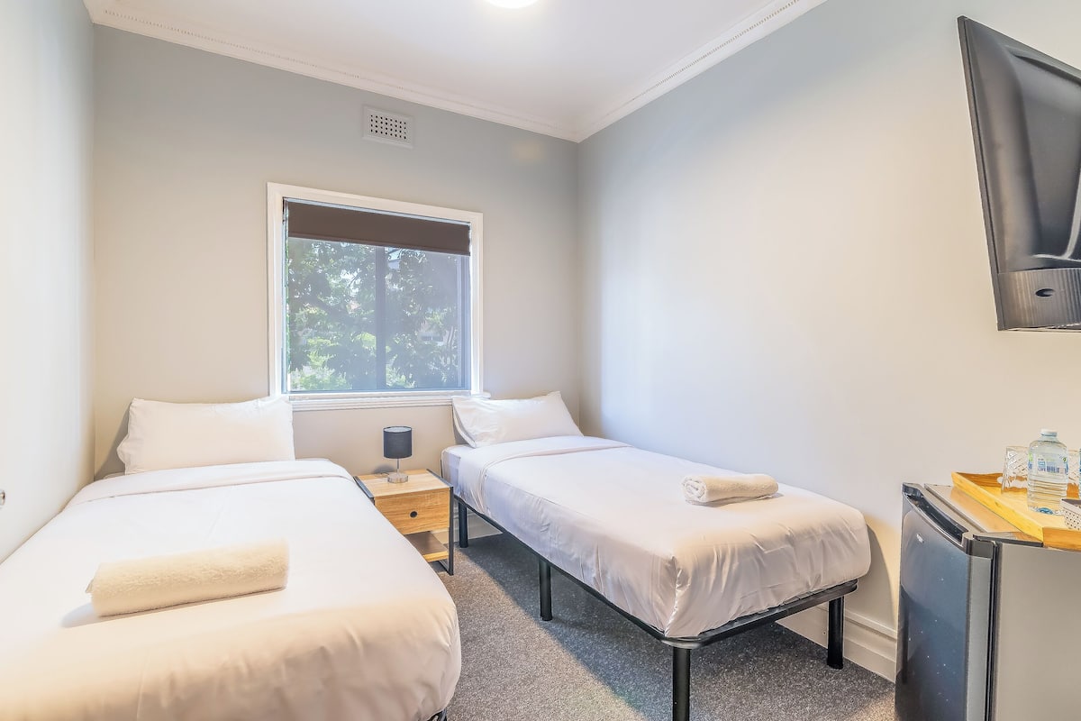 Un dormitorio con dos camas, una ventana, un escritorio y un televisor.