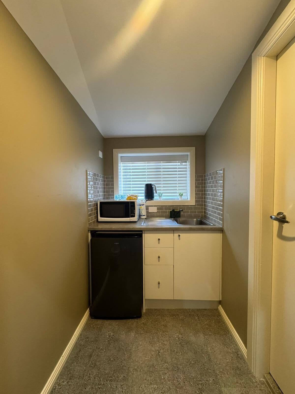 A compact kitchen with a dishwasher, a microwave, and a sink.