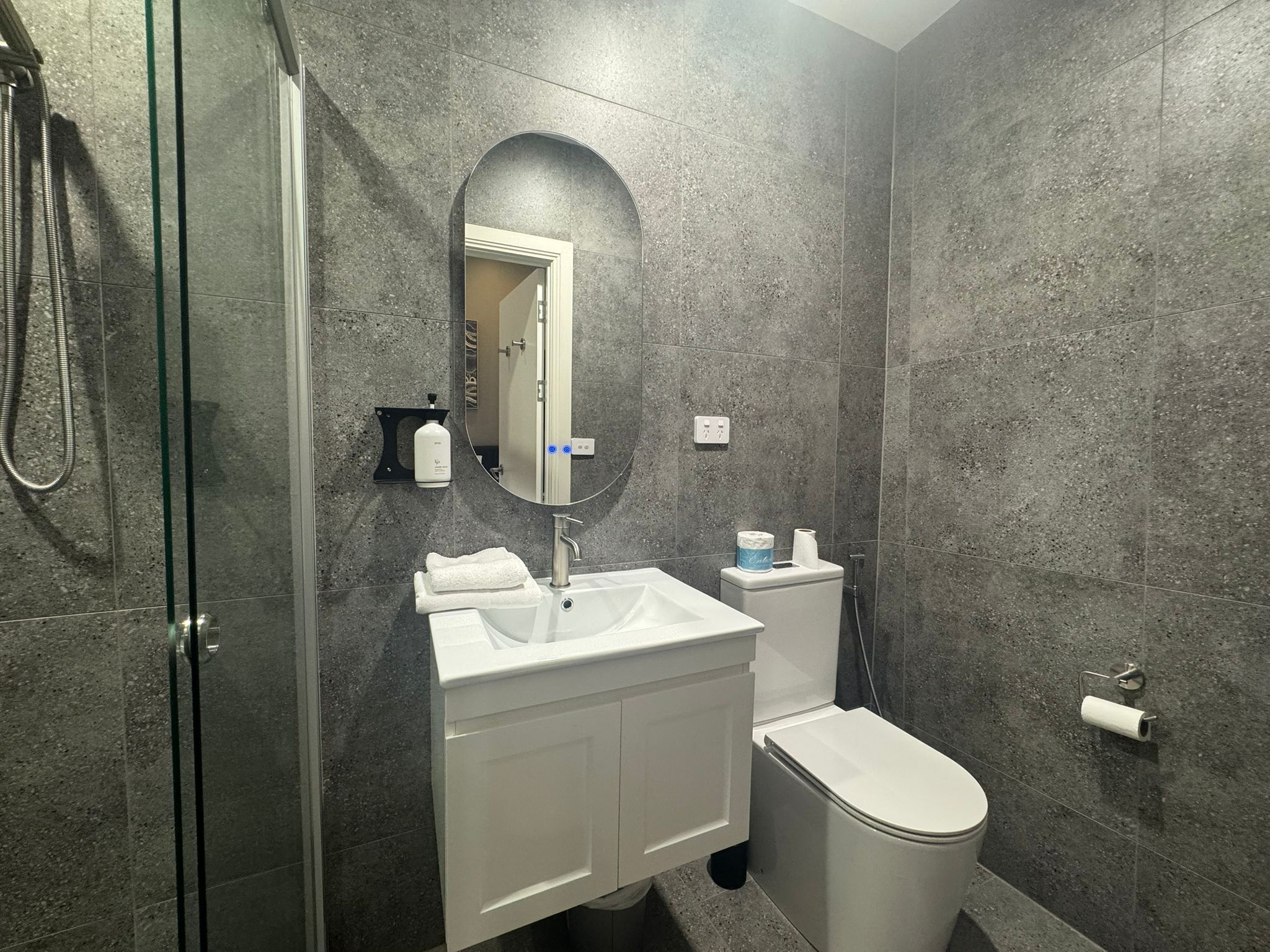 A modern bathroom with a glass shower enclosure, a white sink, and a toilet.