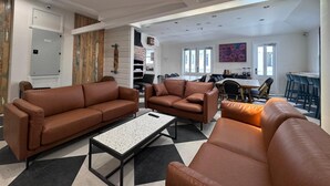 A modern living room with brown leather sofas, a coffee table, and a dining area with chairs and a table. - K2 Brisbane (Spring Hill)