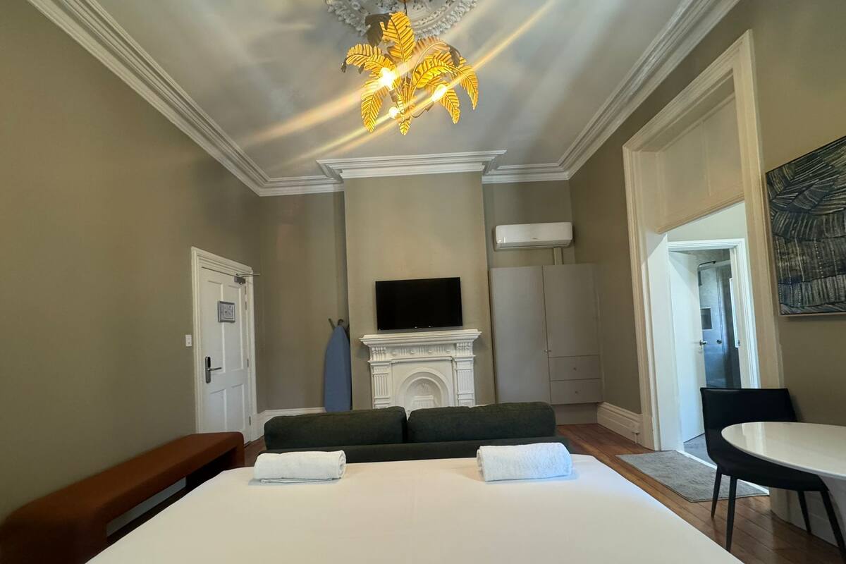 Una habitación de hotel con una cama grande, chimenea, televisor y zona de comedor.
