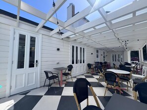 An outdoor patio with a checkered floor, white walls, and multiple tables and chairs. - K2 Brisbane (Spring Hill)