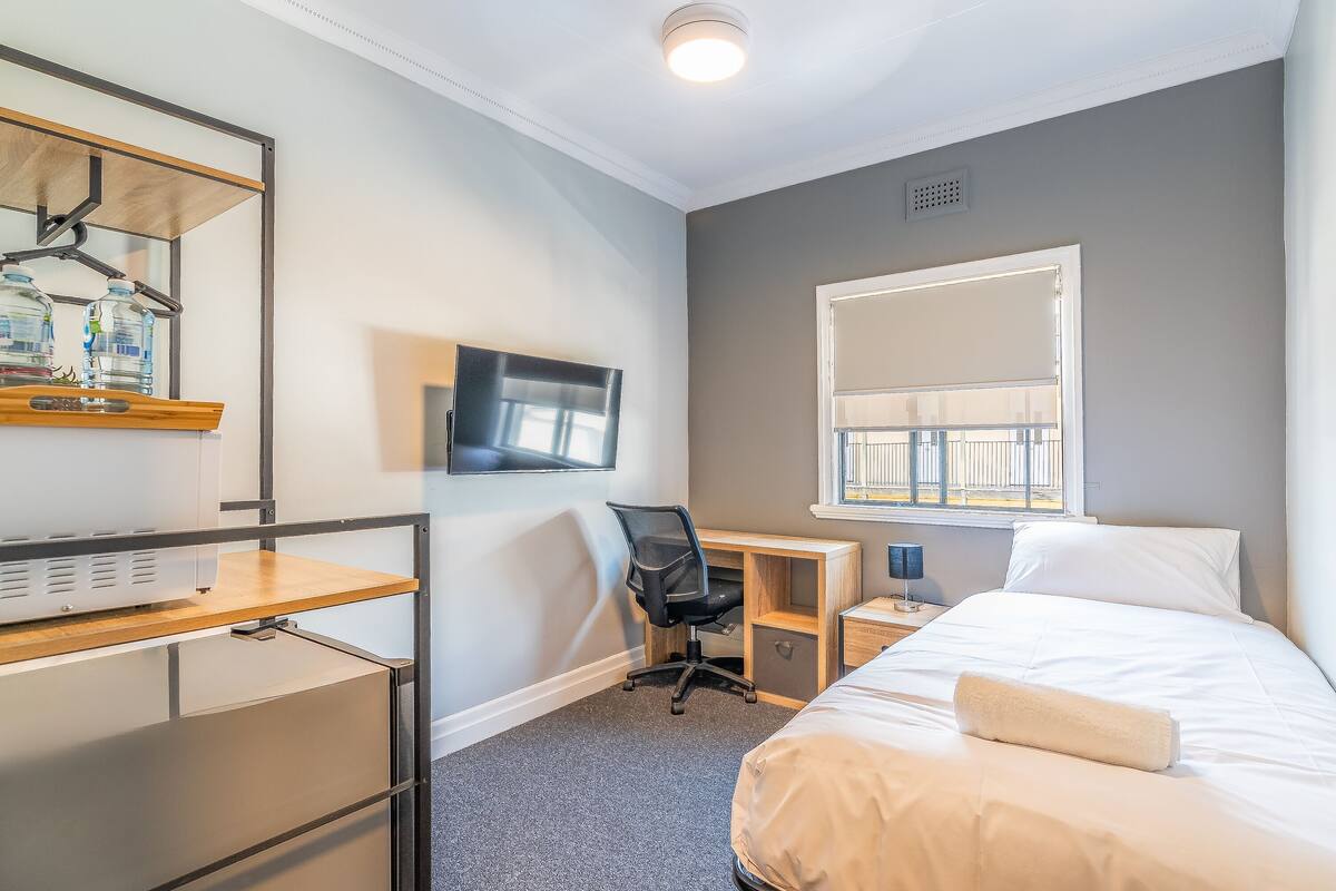 Habitación de hotel con cama, escritorio con silla, televisión y ventana con vistas.