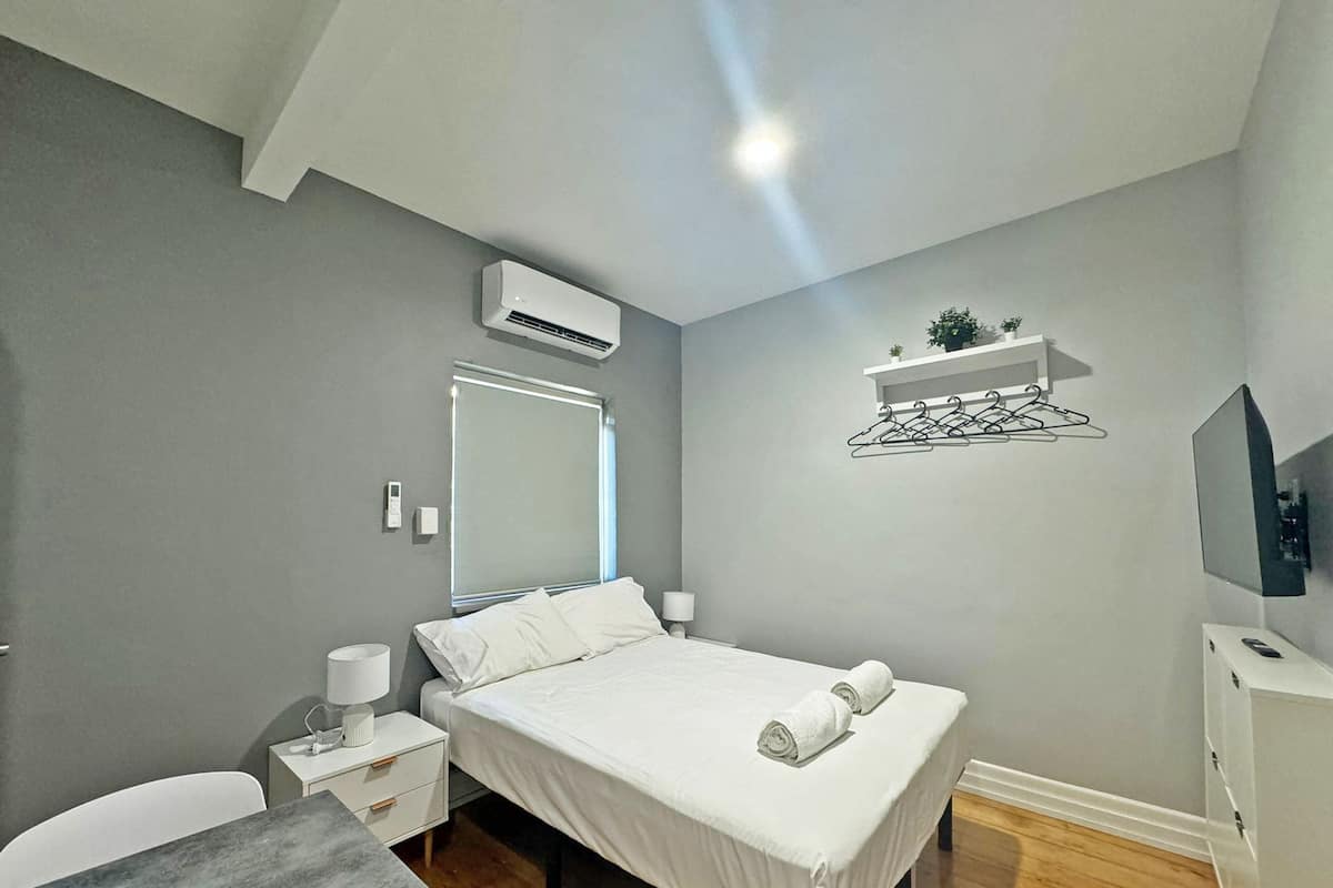 Un dormitorio moderno con cama, mesitas de noche, escritorio y espejo.