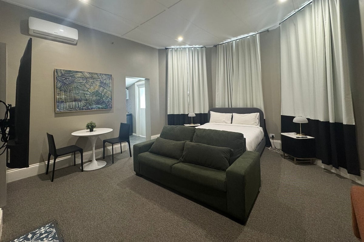 Una habitación de hotel moderna con una cama, un sofá, una mesita y una silla.
