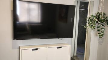 A flat-screen TV mounted on a wall, a mirror, and a cabinet with drawers.