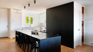 A modern kitchen with a central island, black chairs, white cabinets, and a dark accent wall. - SNØFALL@CAMELBACK (Tannersville)