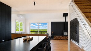 A modern kitchen with a long dining table, a large window with a view, and a fireplace. - SNØFALL@CAMELBACK (Tannersville)