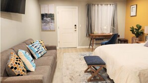 Un dormitorio con una cama, un escritorio, una silla, un sofá y una mesita.