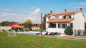 A two-story house with a swimming pool, outdoor seating, and a tennis court. - Holiday apartment with air conditioning (Barban)