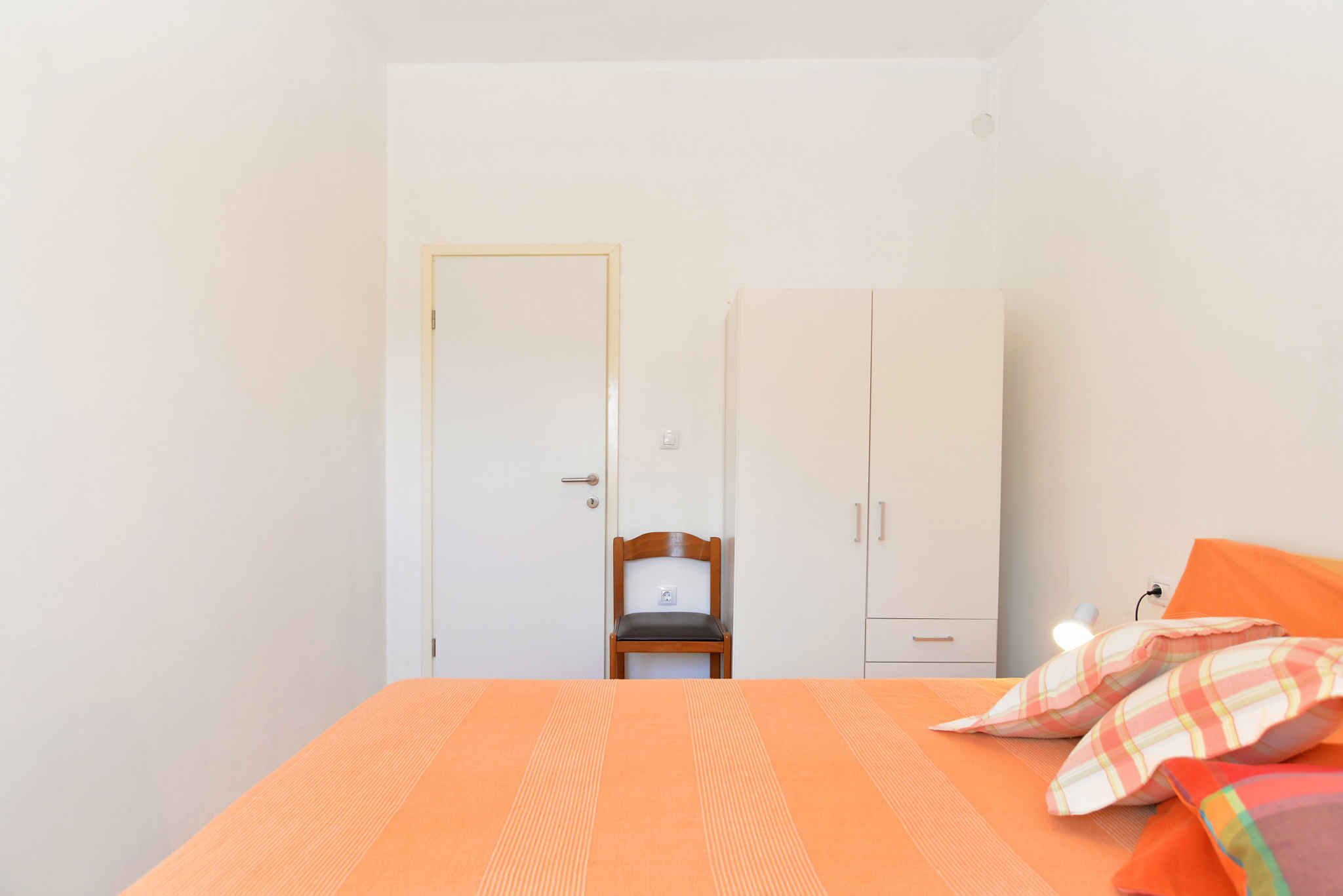 Une chambre à coucher avec un lit, une chaise, une armoire et une porte.