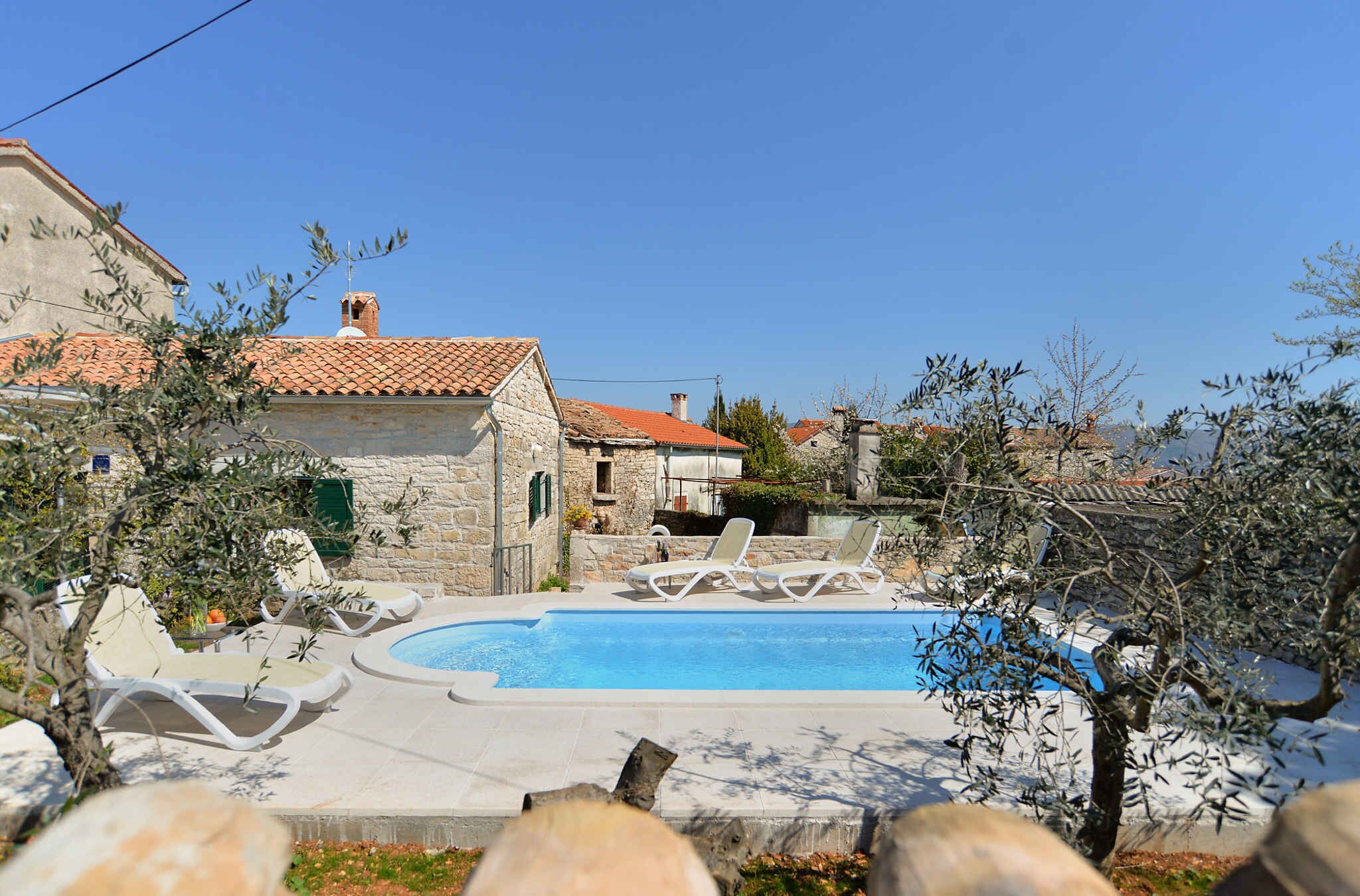 Un espace piscine avec des chaises longues et, en arrière-plan, un bâtiment en pierre.