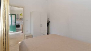 Un dormitorio con cama, un armario y una puerta que da a una cocina.