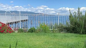 A grassy area with a white fence and a view of a body of water and mountains in the background.