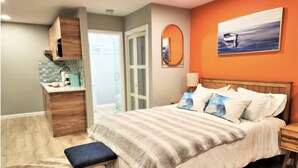 A bedroom with a bed, a bench, a nightstand, and a painting on the wall.