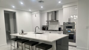 Una cocina moderna con una isla grande, electrodomésticos de acero inoxidable y taburetes de bar.