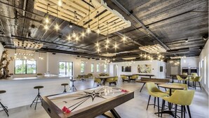 Amplio espacio interior con mesa de fútbol, sillas amarillas e iluminación colgante.