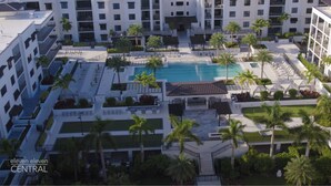 Un hotel moderno con varios pisos, una piscina central y palmeras.