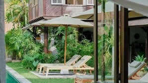 A wooden house with a balcony, a pool, and lounge chairs. - Legian 6BR Villa 16px Big Group Walk to 66 Beach (Bali)