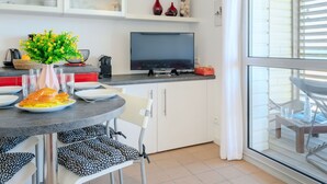 A modern kitchen with a dining area, white cabinets, a flat-screen TV, and a large window. - Lovely apartment for 4 people with WIFI, TV, balcony and pets allowed (Mimizan)