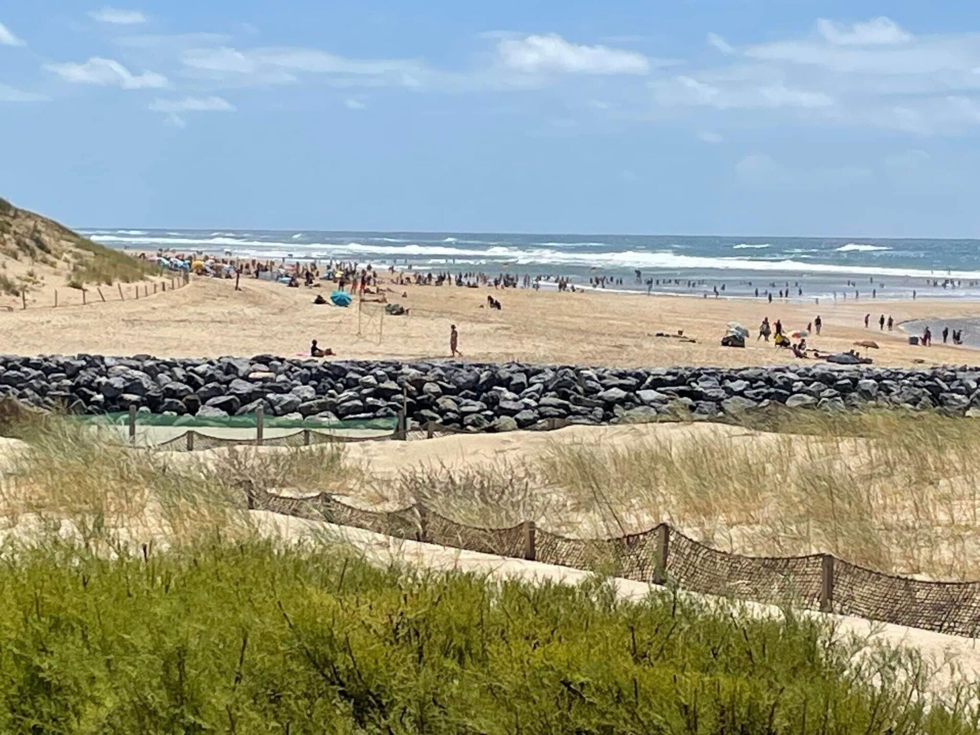 Een strand met een rotsbarrière en een grasveld voor.