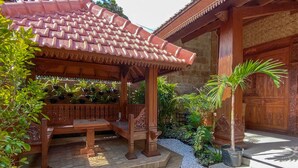 A traditional wooden structure with a tiled roof, surrounded by potted plants and a small garden area. - ReVive by Snooze (Banyuwangi)