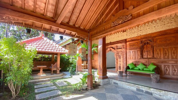 A covered outdoor area with a wooden bench, a small table, and a green sofa. - ReVive by Snooze (Banyuwangi)
