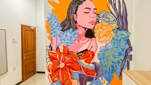 A hallway with a mural featuring a person surrounded by floral and leaf patterns. - ReVive by Snooze (Banyuwangi)