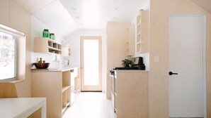 A modern kitchen with wooden cabinets, a countertop, and a door leading to another room.