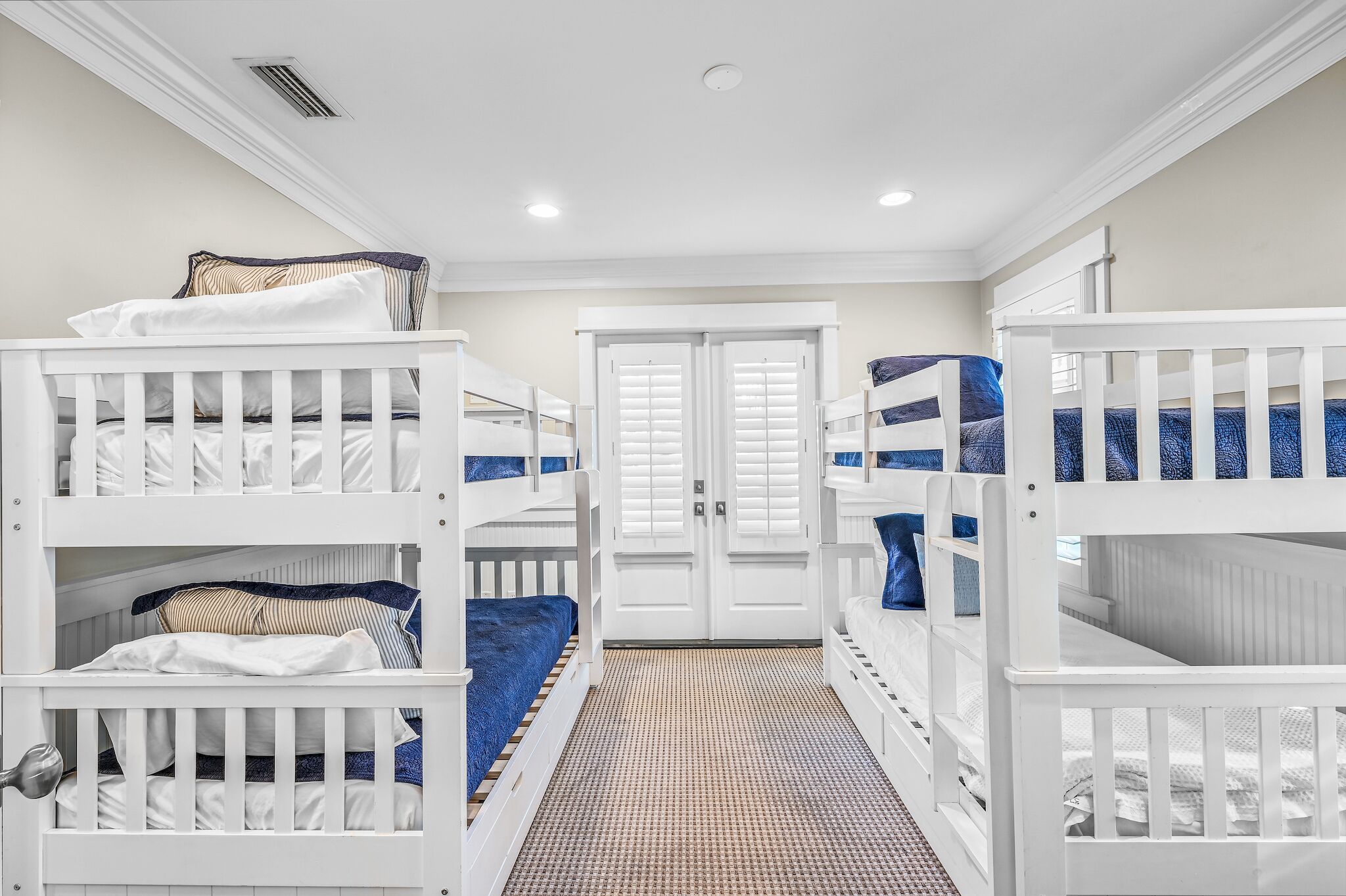 A room with bunk beds, white railings, and a patterned floor.