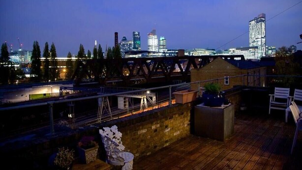 Una terraza en la azotea con vistas al horizonte urbano al anochecer.