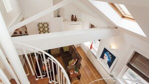 Un interior de varios niveles con una escalera, suelo de madera y un comedor con una mesa y sillas.