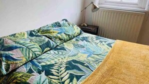 Un lit avec une couvre-lit à motifs tropicaux et une couverture jaune.