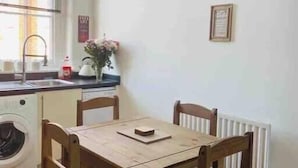 Une petite cuisine équipée d’un lave-linge, d’un évier et d’une horloge murale.